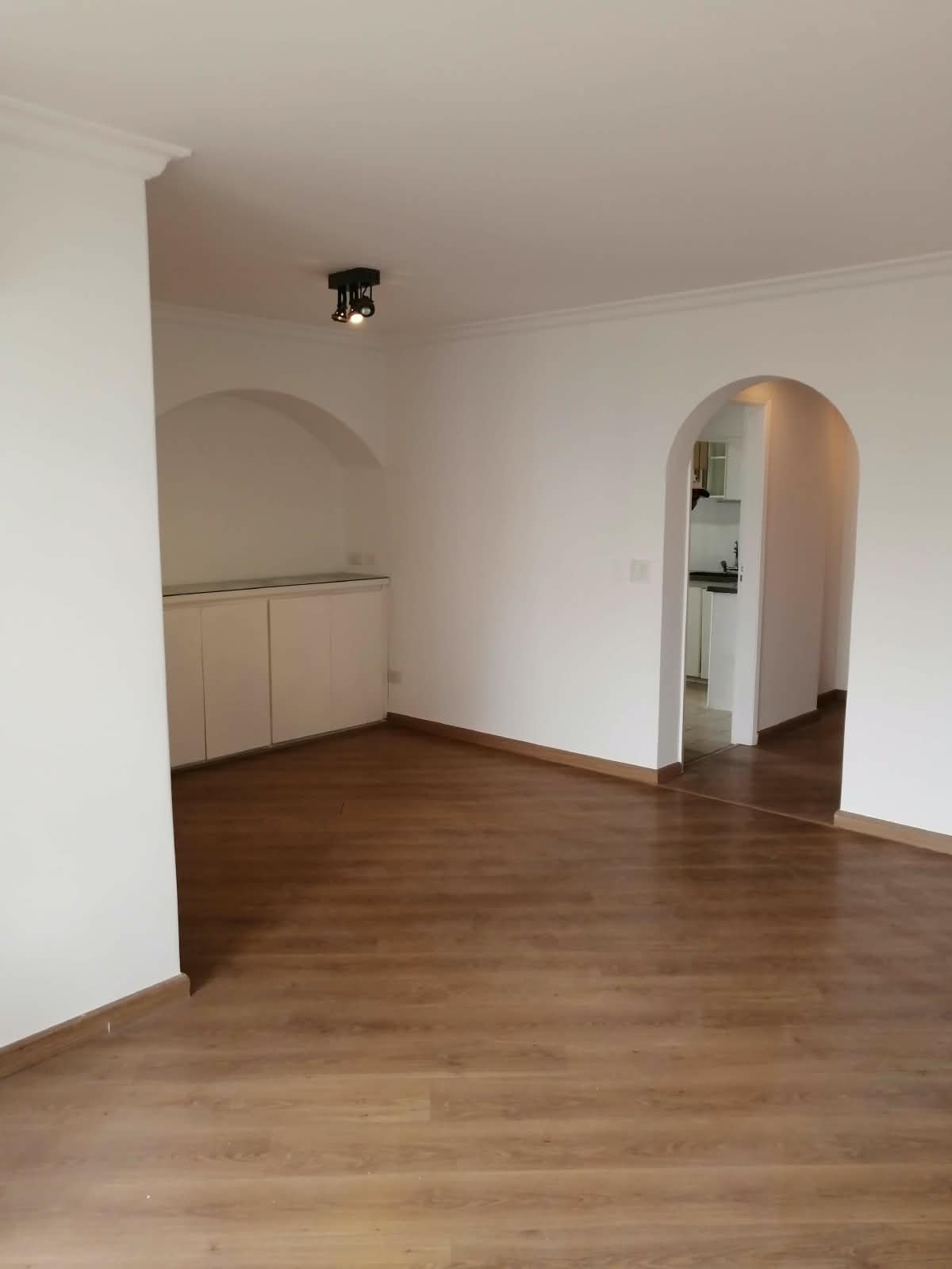 Sala após pintura, paredes brancas e piso de madeira