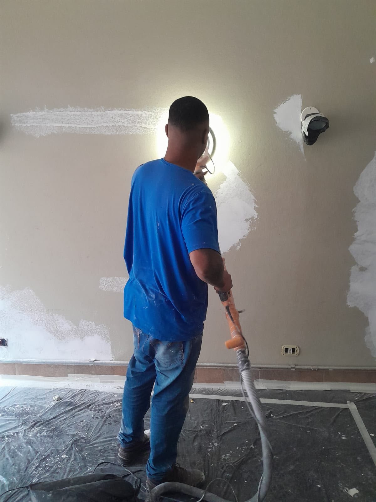 Profissional lixando parede com sistema a vácuo para reduzir a poeira